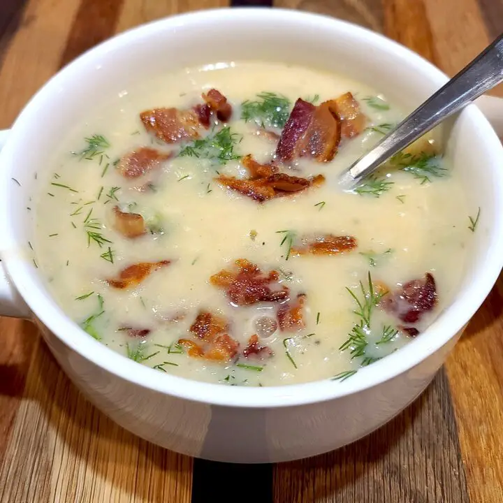 Potato Leek Dill Soup sprinkled with fresh dill and bacon in a white bowl