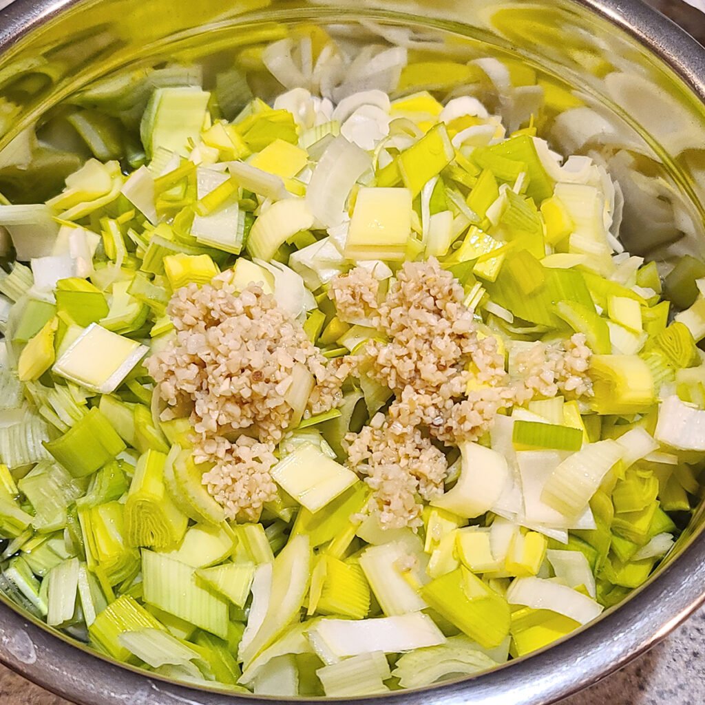 Sliced leeks and minced garlic in a metal bowl