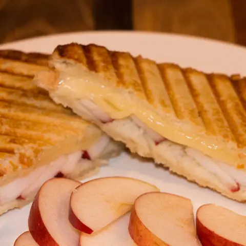 apple fontina honey grilled cheese sandwich recipe on a white plate with apple slices in front