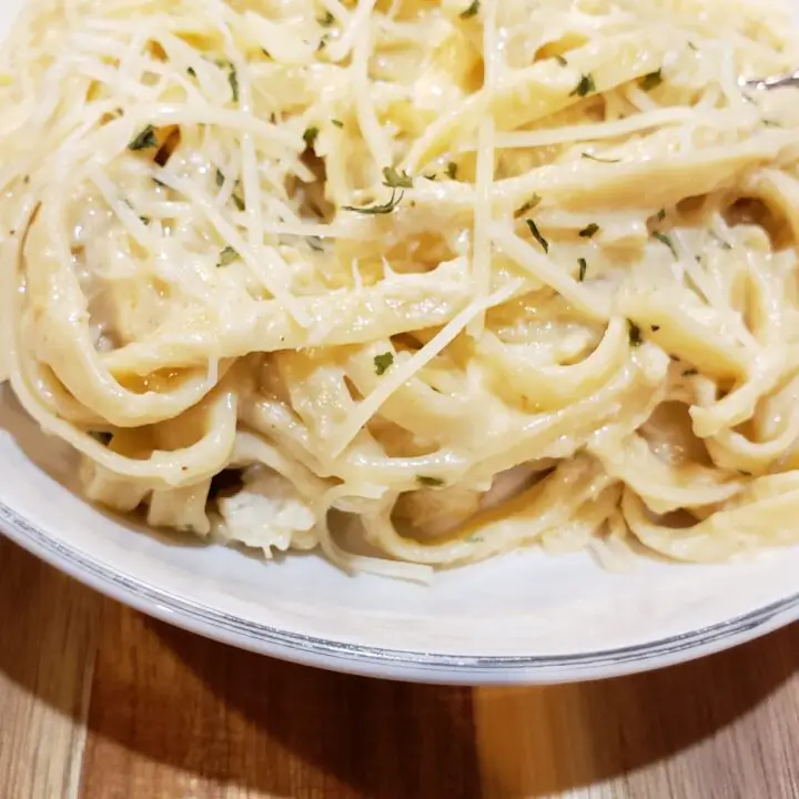 Cajun Crab Alfredo in a white bowl on a wood board