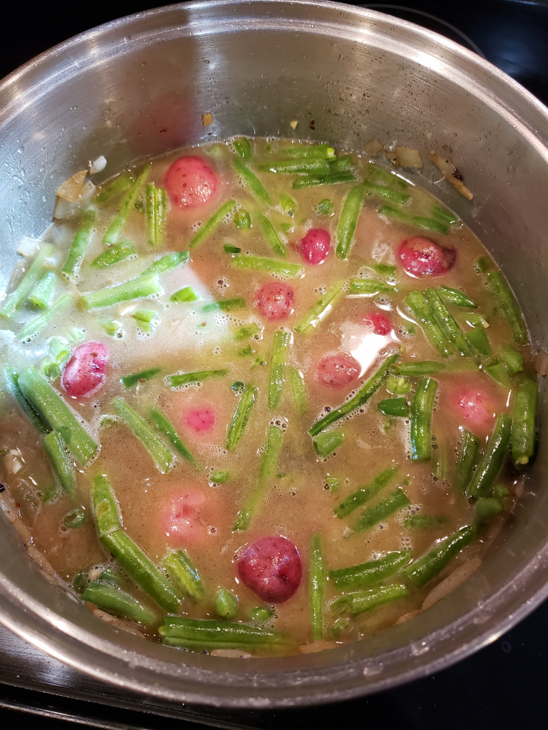 green beans and red potatoes in a pot of chicken broth